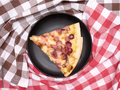 Two slice of pizza blanco. Comfortable home eating. Background of two dishcloth, red and brown colors on the wooden table. Top view