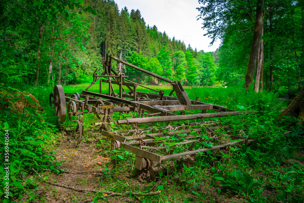 Alte benutzte und rostige Egge am Rand einer Waldlichtung im bayerischen Wald Alte benutzte und rostige Egge am Rand einer Waldlichtung im bayerischen Wald