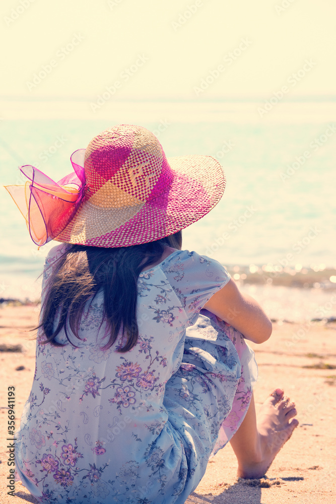Jeune fille au chapeau regardant la mer.