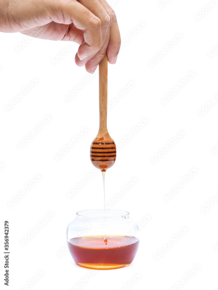 Dipper honey wooden stick in hand with honey drop into to glass jar Dipper honey wooden stick in hand with honey drop into to glass jar