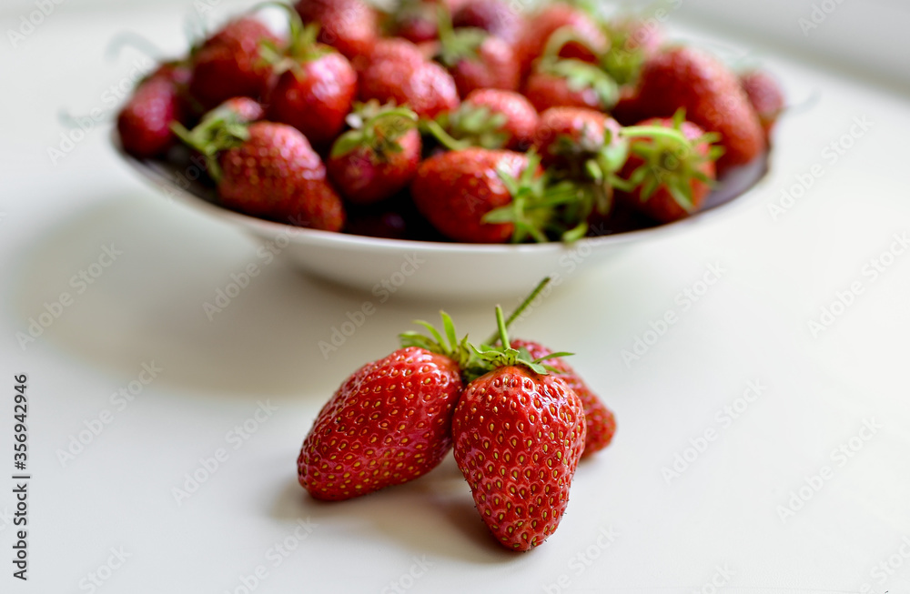 A lot of red, juicy strawberries on a plate. Red berries on a white background. Natural eco-product.