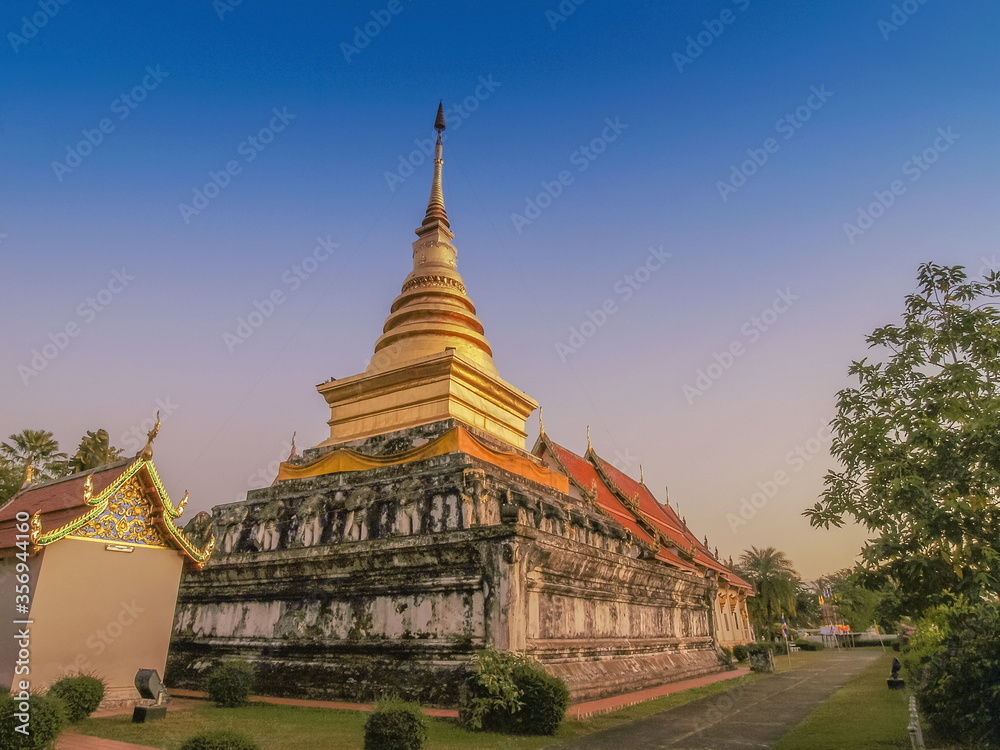 view of golden pagoda (Chedi) with blue sky background, Wat Phra That Chang Kham Voravihara, Nan Province, northern of Thailand.