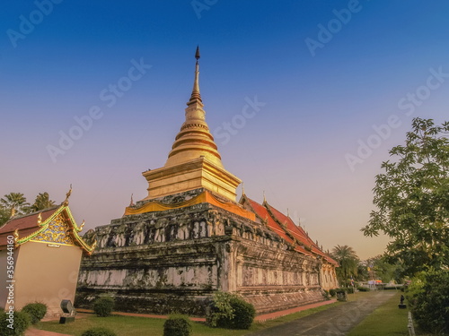view of golden pagoda (Chedi) with blue sky background, Wat Phra That Chang Kham Voravihara, Nan Province, northern of Thailand.