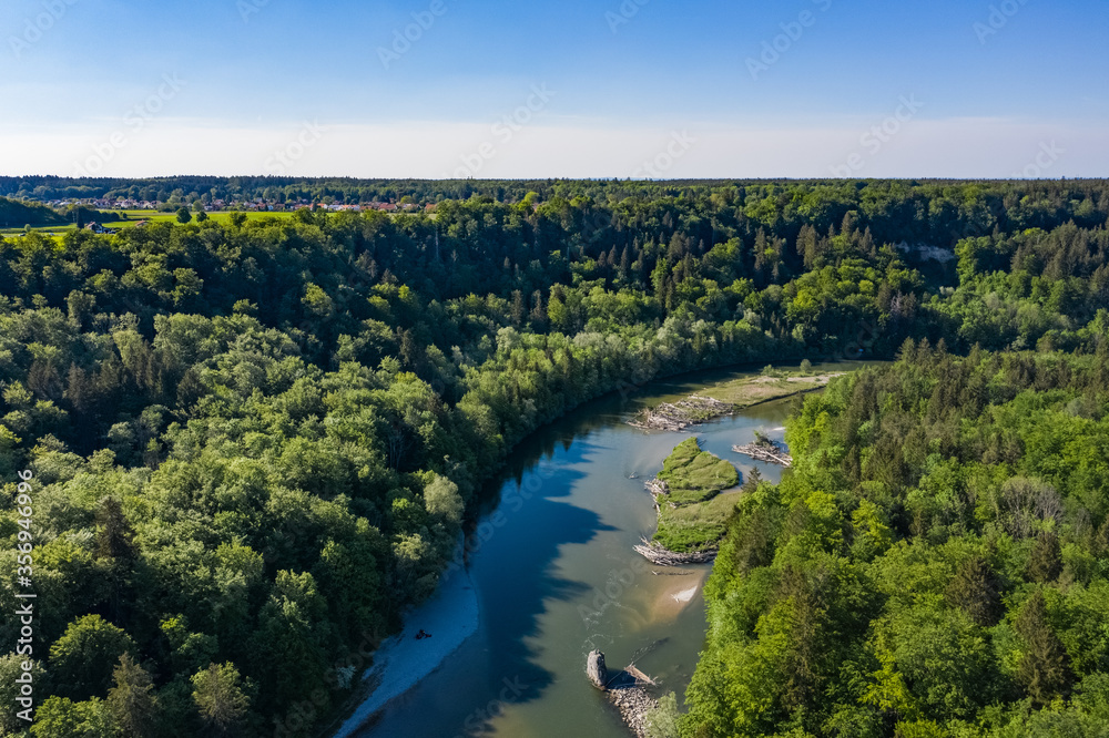 High aerial view of Isar river in Spring with forest and amazing ecological landscape around. Drone bird view of german river.