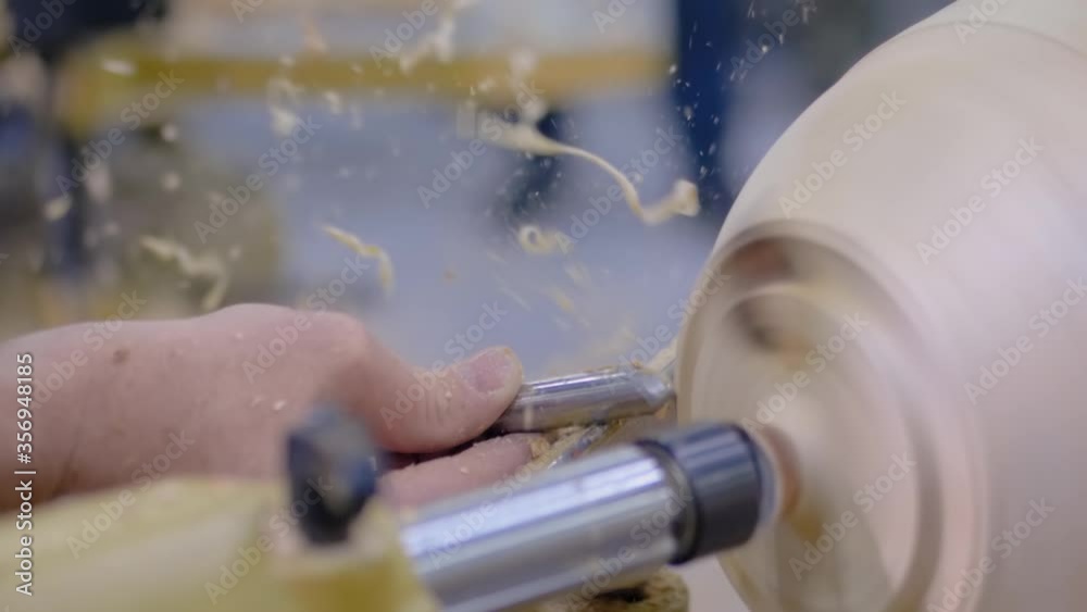 Super slow motion: professional man carpenter holding skew chisel, shaping piece of wood and using wood turning lathe at workshop - close up. Design, carpentry, craftsmanship, manufacturing concept Super slow motion: professional man carpenter holding skew chisel, shaping piece of wood and using wood turning lathe at workshop - close up. Design, carpentry, craftsmanship, manufacturing concept