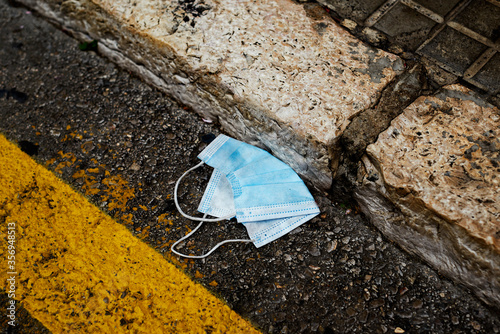 used surgical mask thrown on the asphalt