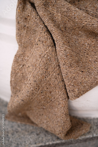 knitted scarf from wool, textured patterns on the fabric, brown canvas from wool, handwork, knitted winter scarf,