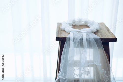 wedding white bridal veil on wooden chair. tulle gathered in hair hoop photo