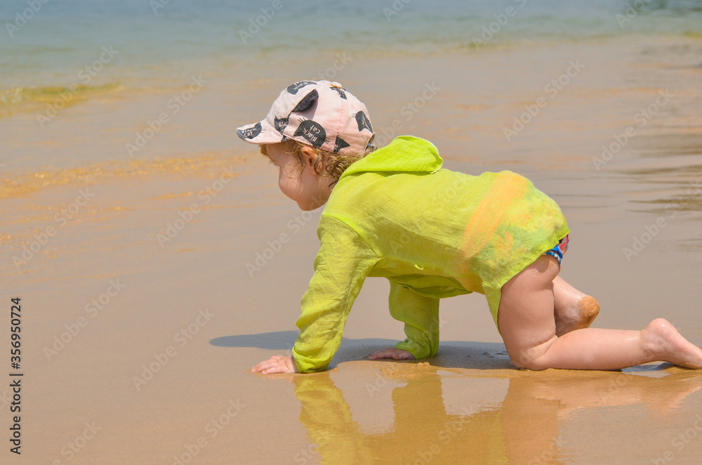 Obraz premium Happy caucasian child on a sandy beach in summer lifestyle. The concept of leisure activity, tourism and happy vacation