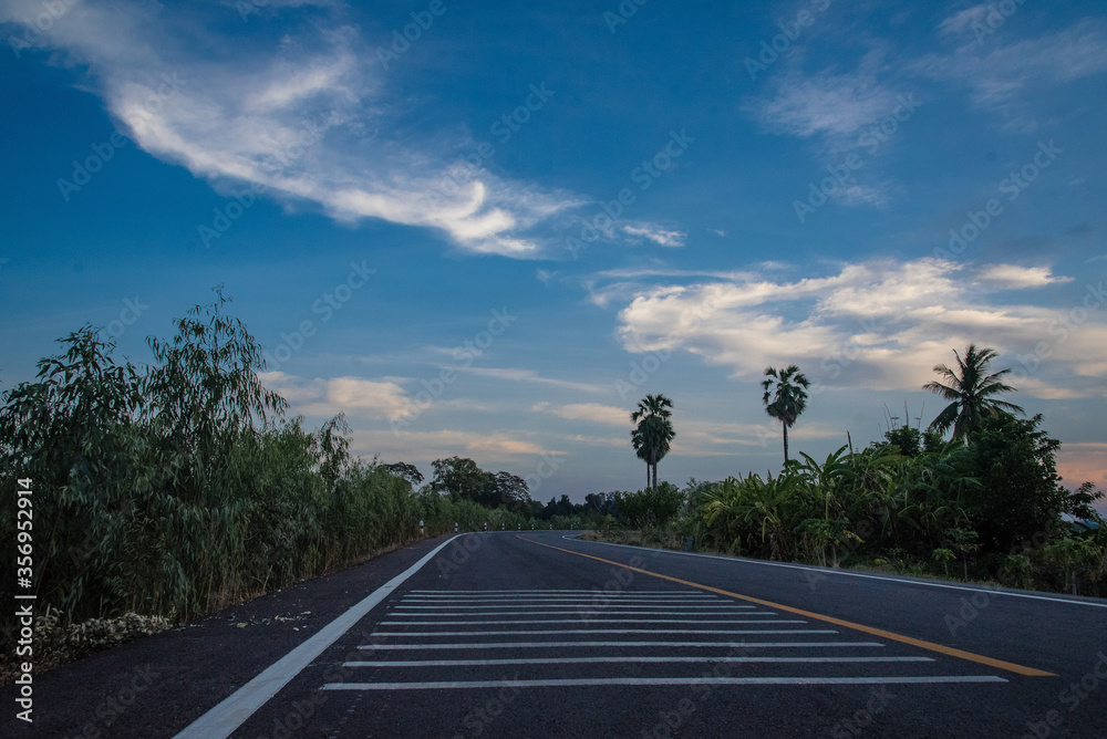 paved road leading to the evening clouds