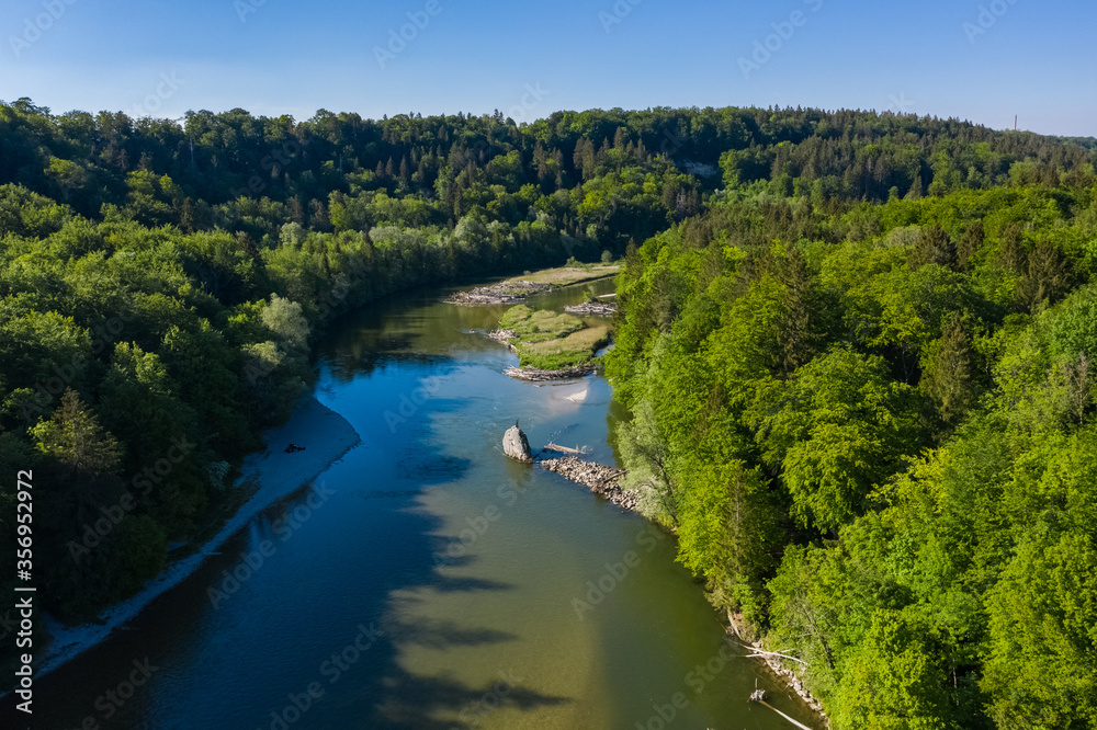 Aerial drone view of Isar river flowing across bavarian forest seen from above in the south of Munich near Baierbrunn town.
