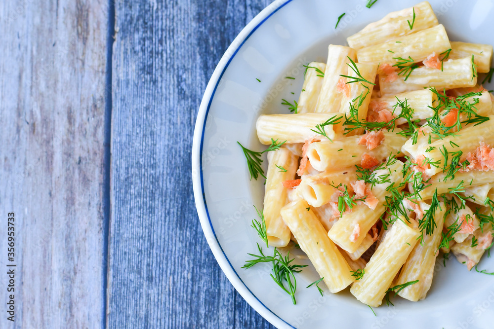 Italian home made macaroni pasta with smoked salmon , creamy sauce and fresh dill on wooden background Italian home made macaroni pasta with smoked salmon , creamy sauce and fresh dill on wooden background