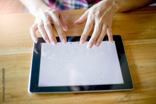 Woman using tablet computer in cafe, close up finger on tablet 