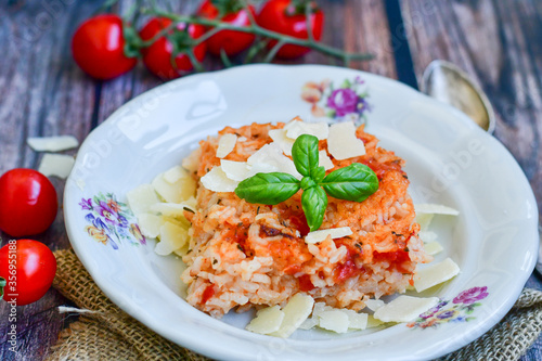 Home made italian oven baked tomato risotto with a fresh leaf of basil and parmesan cheese 