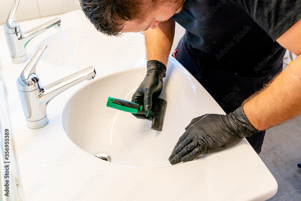 professional cleaner removing dirt stains from a ceramic bathroom sink