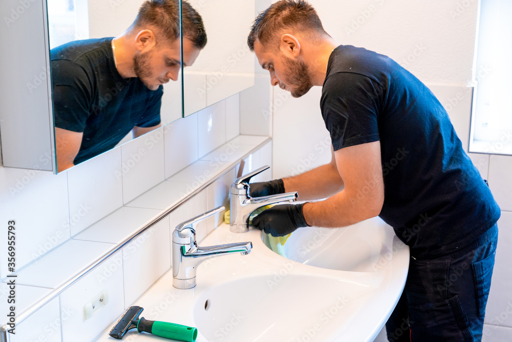 man cleaning a bathroom sink with a scraper blade and micro fiber cloth to remove lime and stains man cleaning a bathroom sink with a scraper blade and micro fiber cloth to remove lime and stains