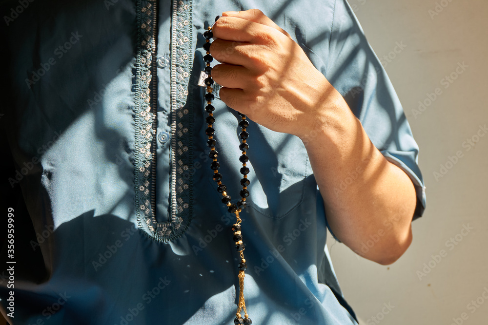 Close up of hand holding black rosary