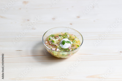 Cold russian soup okroshka in glass bowl on wooden table