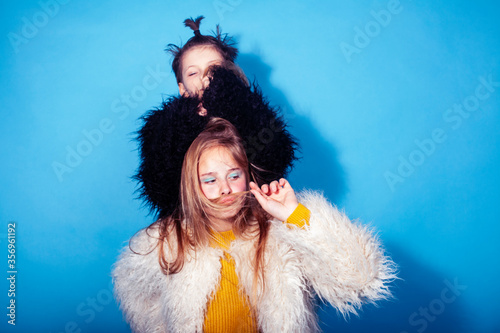 young and pretty fashion models boy and teenage girl posing cheerful on blue background, lifestyle people concept
