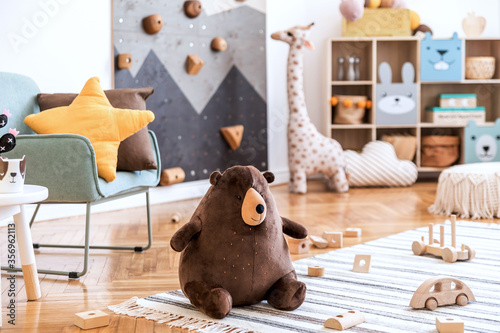 Modern scandinavian interior design of childroom with mint armchair, climbing wall for kids, design furnitures, soft toys, teddy bear and cute children's accessories. Stylish kidroom decor. Template. photo