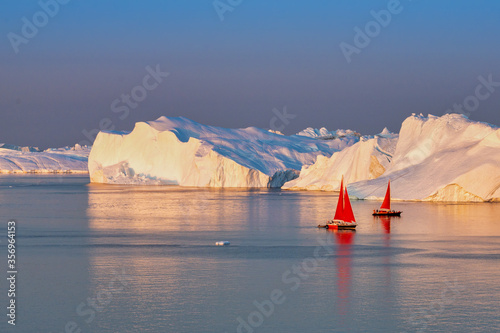 Greenland Ilulissat glaciers at ocean with res sailing boat photo