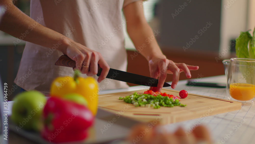 Woman cutting vegetables on wooden board. Smiling lady cooking salad on kitchen