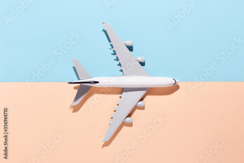 Model airplane on light blue and orange color paper background. Flat lay, top view and copy space for your text