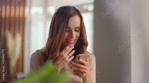 Woman reading message on smartphone at home. Girl using mobile phone on kitchen