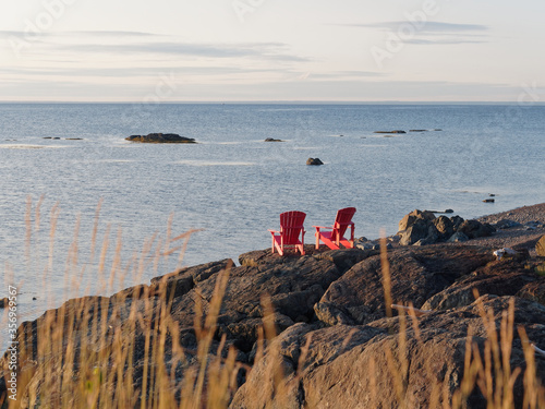 Two red chairs on a rocky coastine at sunrise in Petit-Rocher, New-Brunswick photo