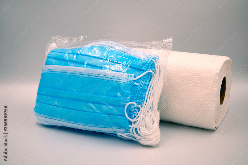 Fototapeta premium Pack of surgical face mask in plastic with tissue roll over white background