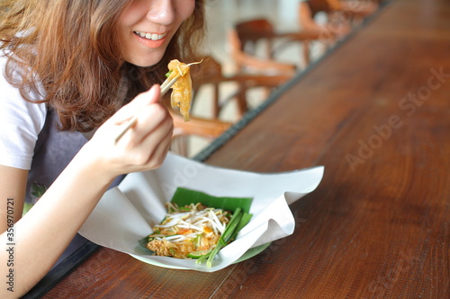 young woman eating a Thai style fried noodle