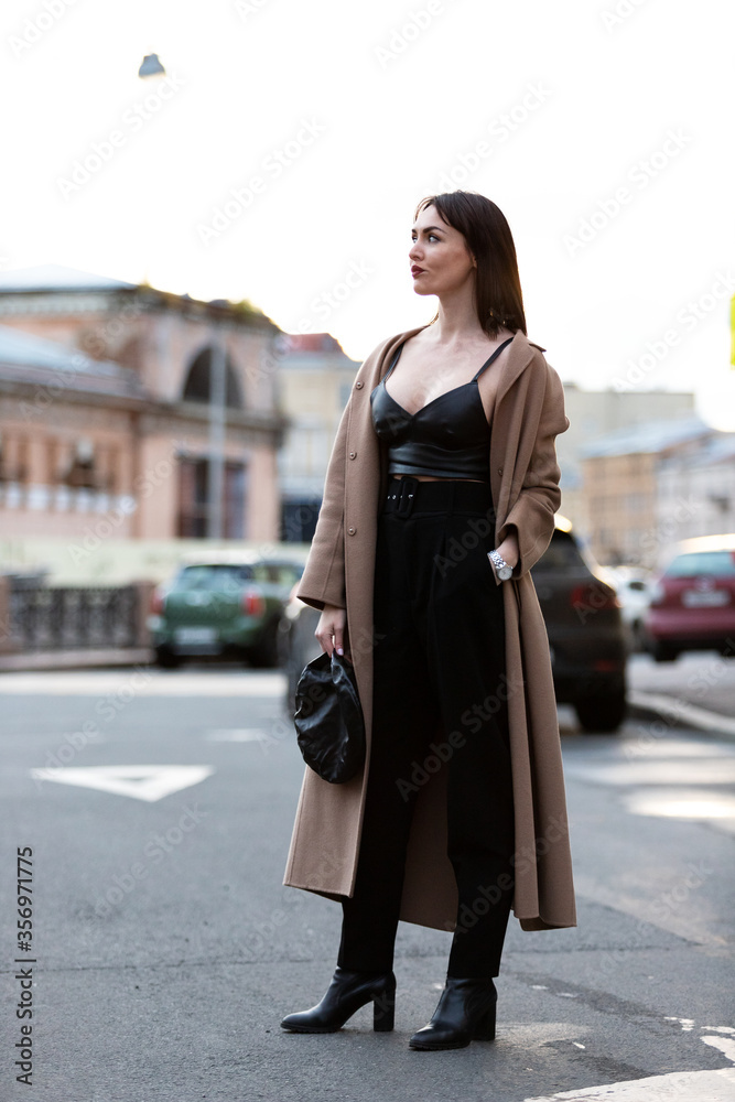 Fototapeta premium Woman in black pantsuit walks on promenade