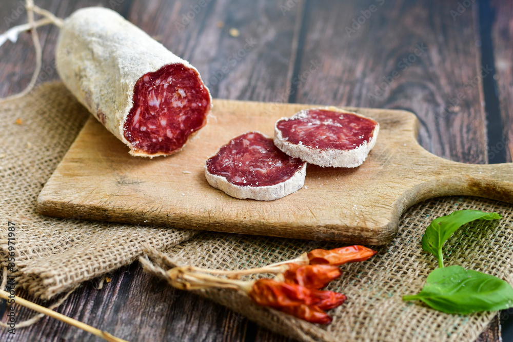 Italian dried artisan pork salami,parmesan cheese ,peperoncino and fresh basil on wooden background .Rustic home made food Italian dried artisan pork salami,parmesan cheese ,peperoncino and fresh basil on wooden background .Rustic home made food