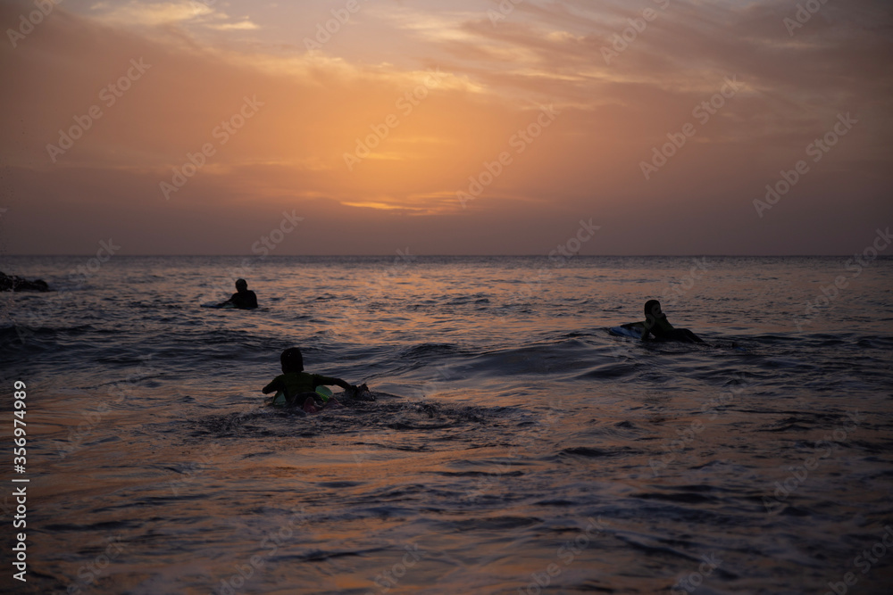 children surf, a group of young surfers catching waves on sunset time. Surfing and sport lifestyle, outdoors activities