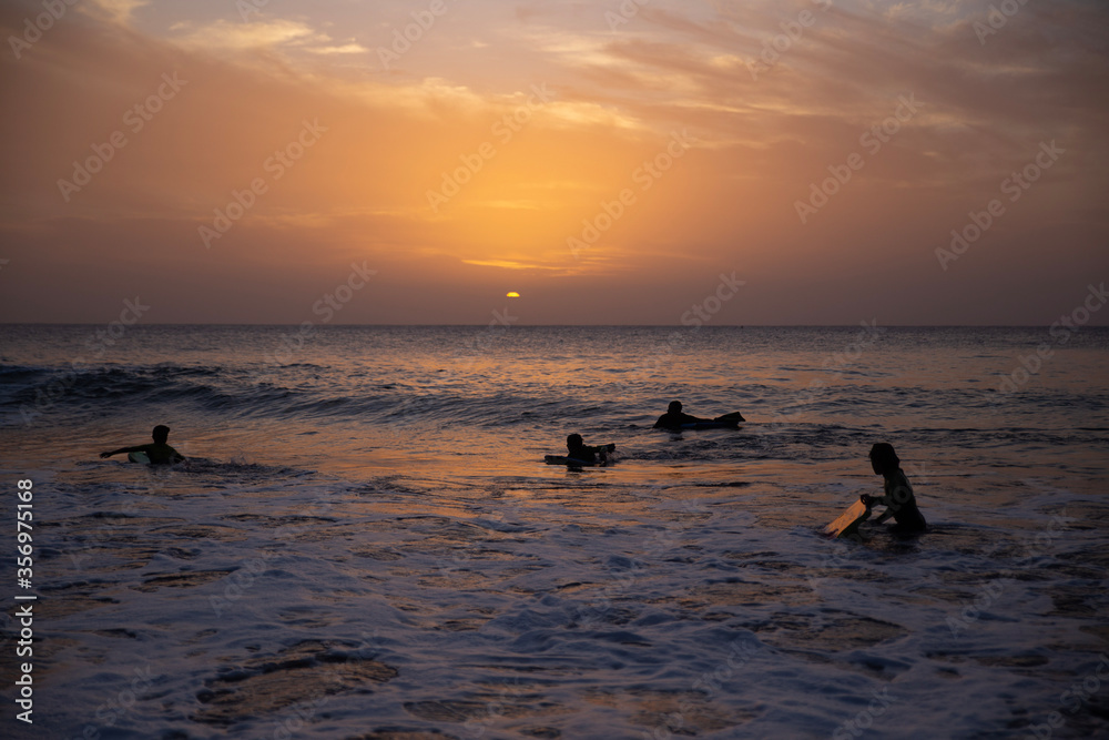 children surf, a group of young surfers catching waves on sunset time. Surfing and sport lifestyle, outdoors activities