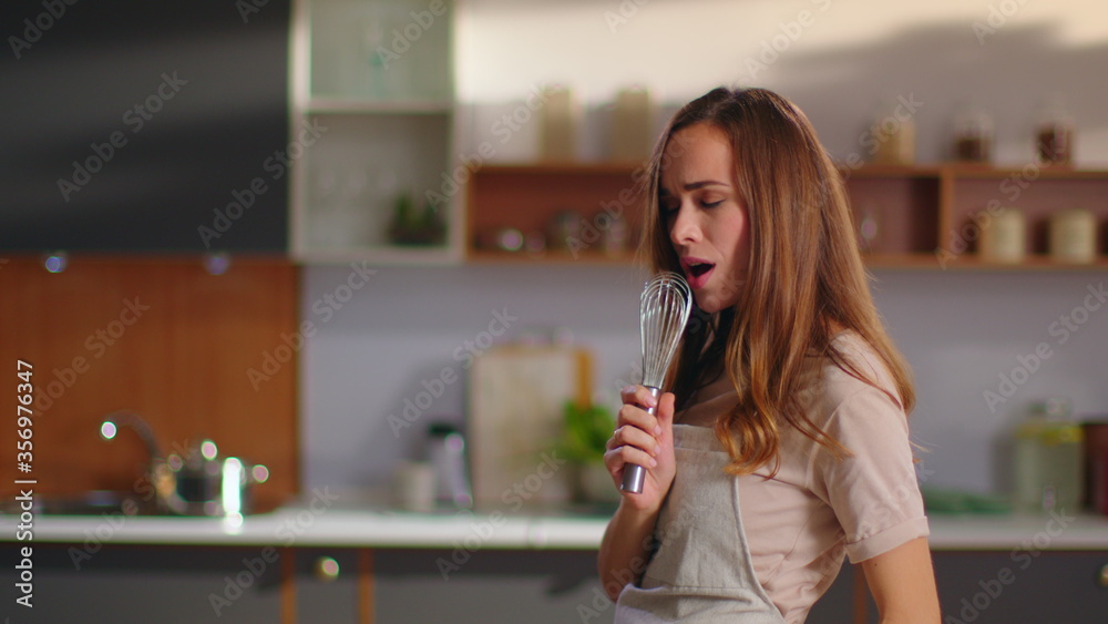 Woman singing song in whisker on kitchen. Girl having fun at home Woman singing song in whisker on kitchen. Girl having fun at home