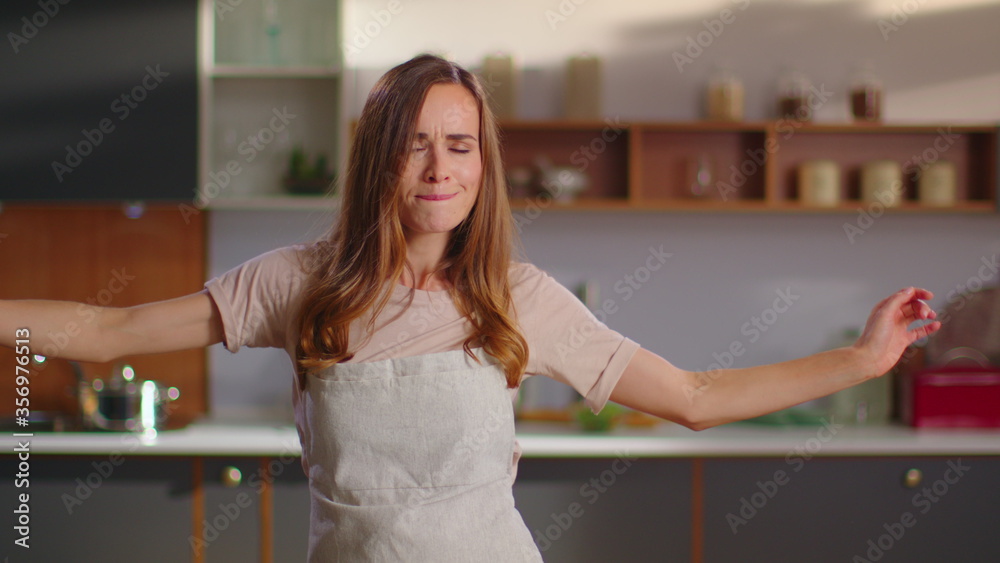 Obraz premium Woman dancing on kitchen. Lady gesturing with whisker in hand at kitchen