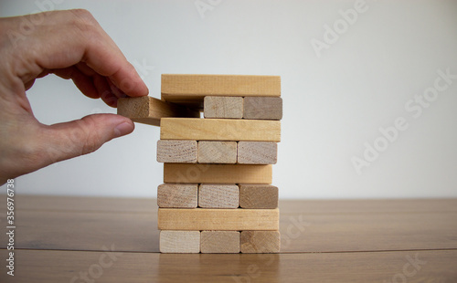 Male hand draws a block from the model of business, made from wood blocks. Alternative risk concept, business plan and business strategy. Insurance concept. White background, copy space.