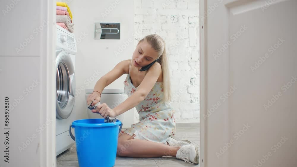 Woman wiping wet floor near leaking washing machine