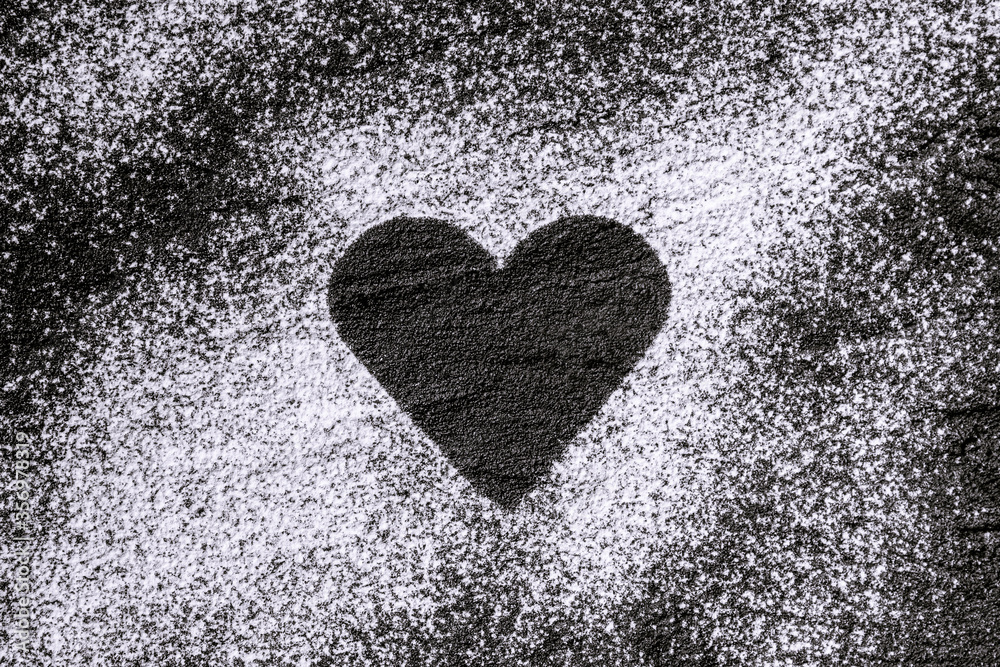 heart made of flour, icing sugar on black concrete