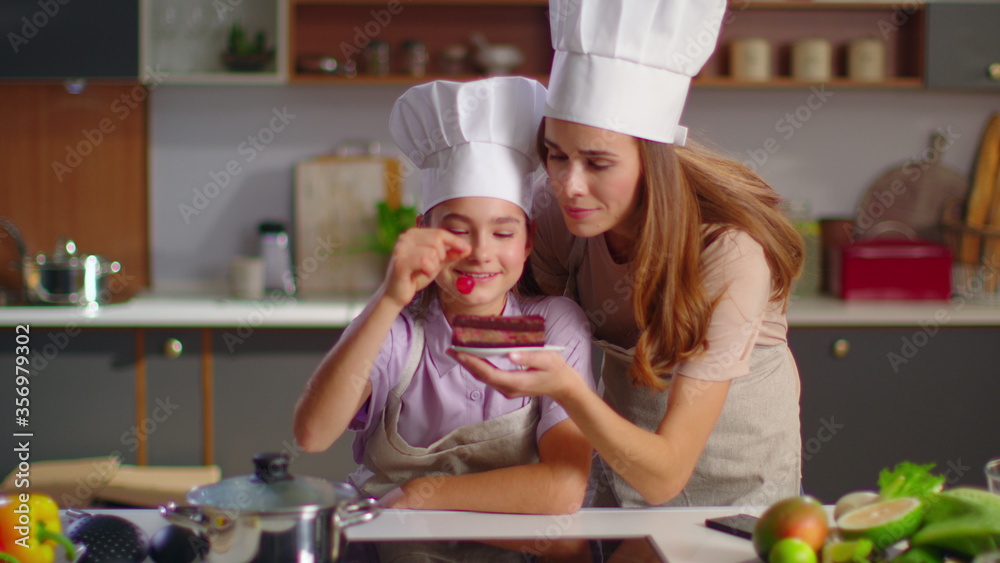 Confectioner and mother putting cherry on cake at kitchen in slow motion Confectioner and mother putting cherry on cake at kitchen in slow motion