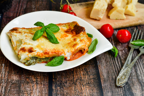   Delicious Home made Lasagna  with minced meat,tomato sauce and spinach  on a wooden rustic  background.Home made italian meal