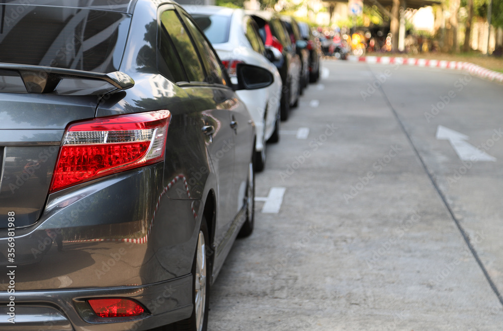 Obraz premium Closeup of rear, back side of black car with other cars parking in outdoor parking area in sunny day. 