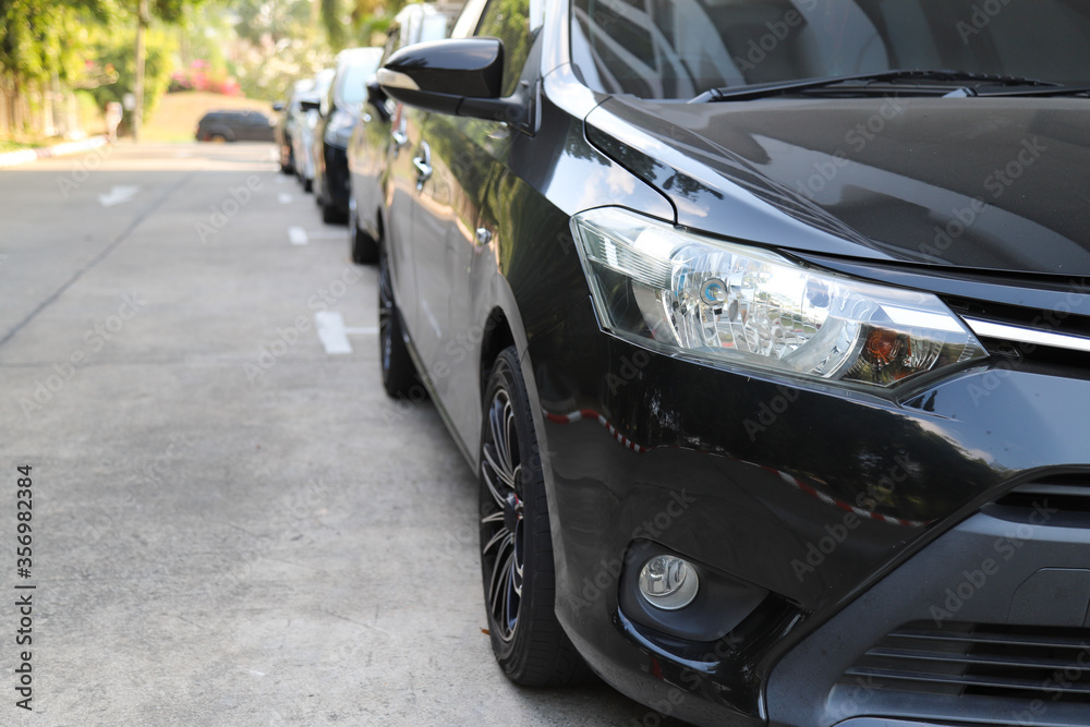 Closeup of front side of black car with  other cars parking in parking area.