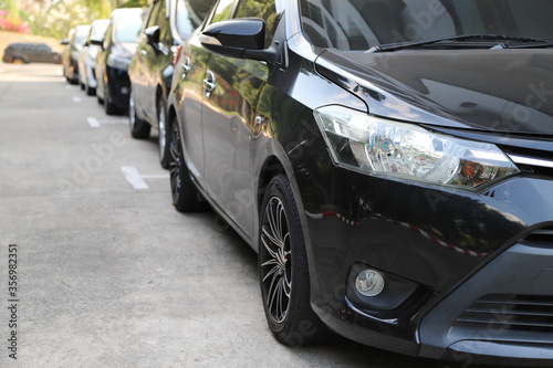 Closeup of front side of black car with  other cars parking in parking area. © Amphon