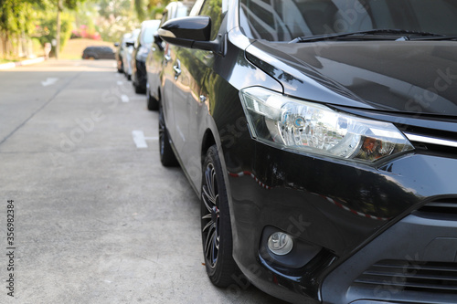 Closeup of front side of black car with  other cars parking in parking area. © Amphon
