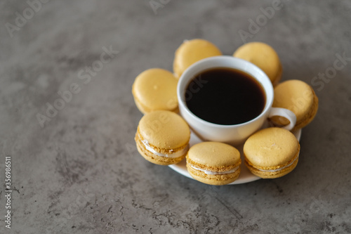 Handful of Delicious Yellow French Macarons on the Table with Cup of Coffee