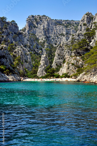 People relaxing on a white beach and in the turquoise waters of a calanque near Marseille in the Mediterranean Sea.