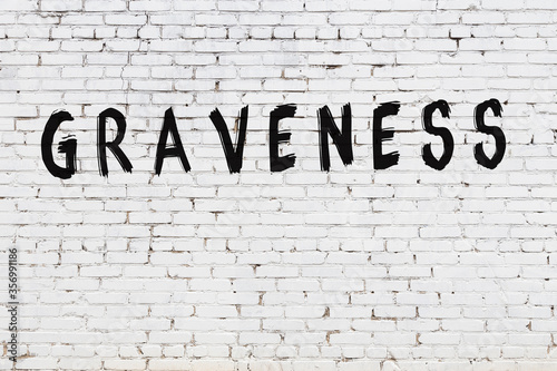 Foto White wall with black paint inscription graveness on it