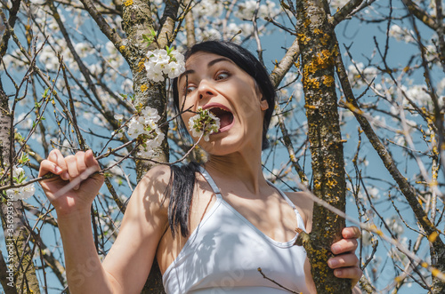 Vegan girl is trying to eat flowers on a flowering tree